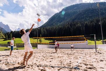 A group of people are playing beach volleyball