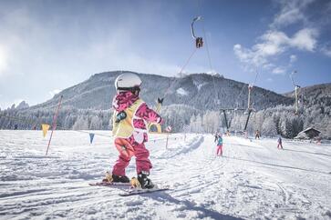 Un bambino risale il pendio con uno skilift a piattello