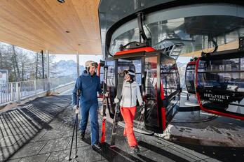 Un uomo e una donna con l’attrezzatura da sci scendono da uno skilift