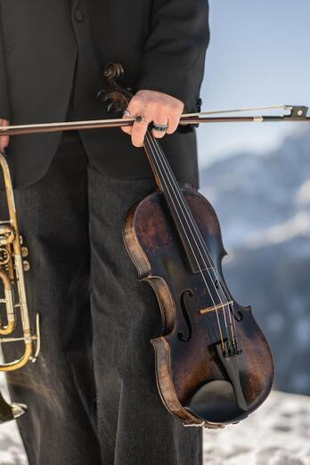 A woman is holding a trumpet in one hand and a violin in the other