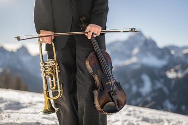 Una donna tiene una tromba in una mano e un violino nell’altra