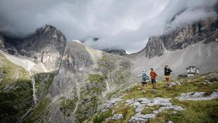 Two women and a man are looking at the Dolomites