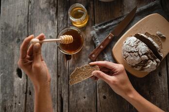 A woman spreads honey on a slice of bread