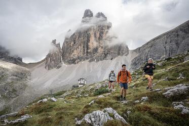 A man and two women are hiking in the Sexten Dolomites
