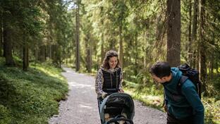 Un uomo e una donna passeggiano nel bosco con un passeggino
