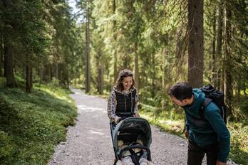 Un uomo e una donna passeggiano nel bosco con un passeggino