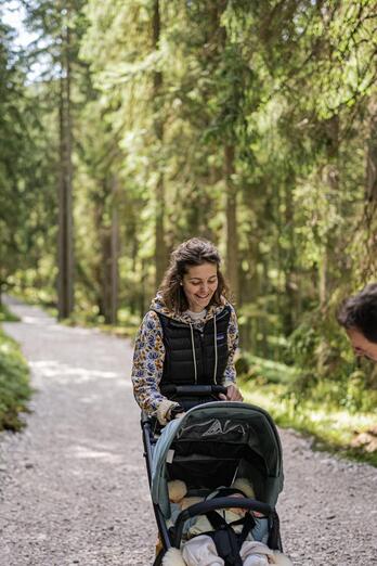 Un uomo e una donna passeggiano nel bosco con un passeggino