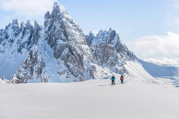 Two people are snowshoeing around the Three Peaks