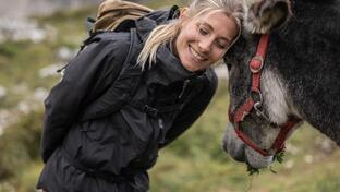 A woman is standing next to a donkey and petting it