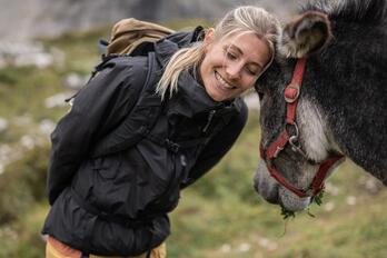 A woman is standing next to a donkey and petting it