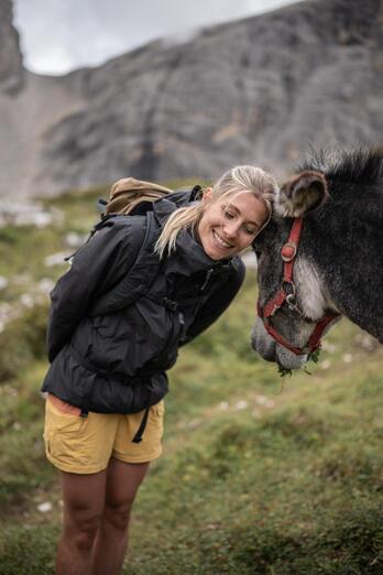 A woman is standing next to a donkey and petting it