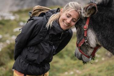A woman is standing next to a donkey and petting it