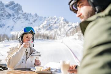 Un uomo e una donna con l’attrezzatura da sci bevono un caffè