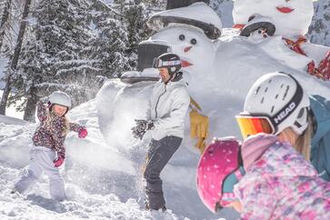 Un uomo gioca con tre bambini nella neve
