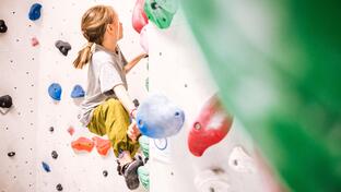 A child climbs on a bouldering wall in a climbing gym