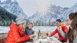 Three women and a man are sitting at a table, enjoying an aperitif